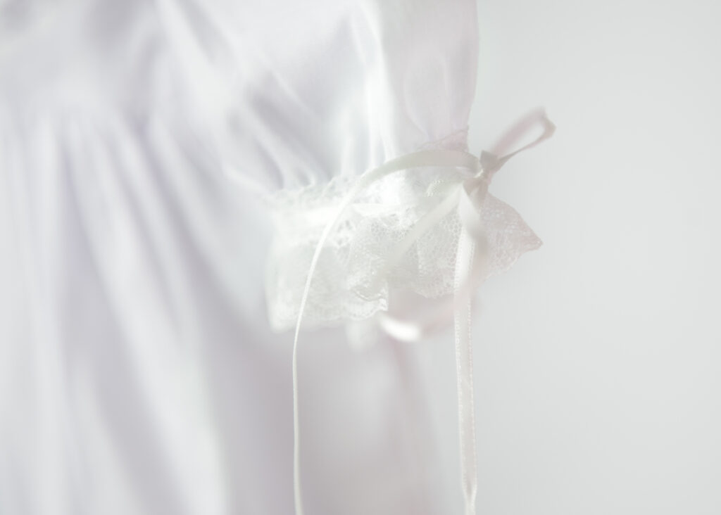 Artistic photo of close up of white lace sleeve with dress of an heirloom child dress.