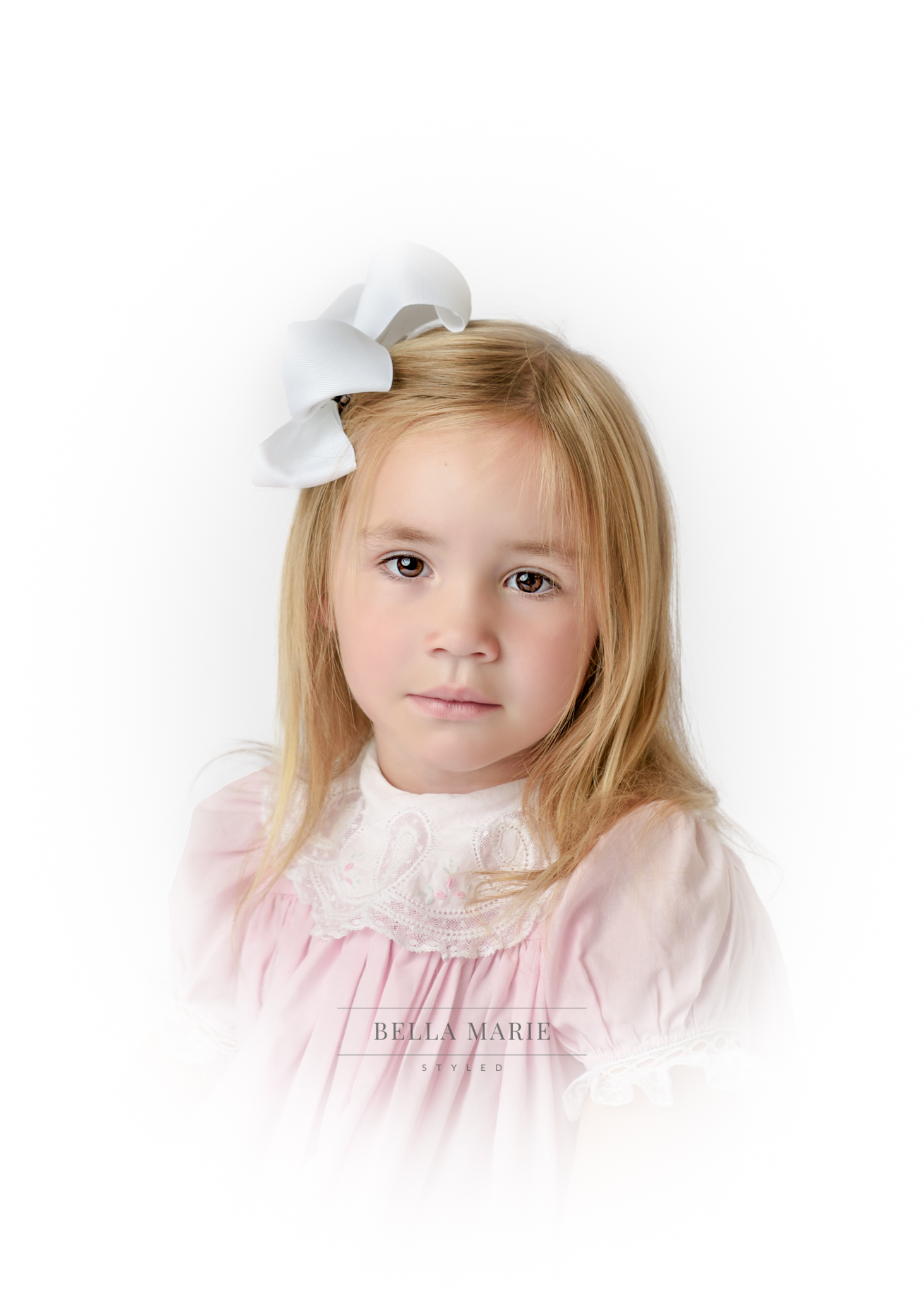 Portrait of little girl with long blonde hair in pink dress with white collar posing on white background for her heirloom portrait.